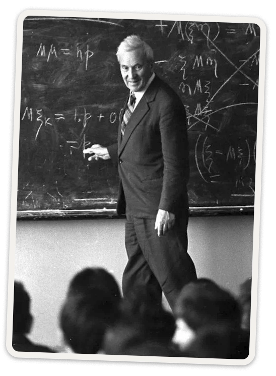 Andrey Kolmogorov in a black suit writing on a blackboard in front of a crowd