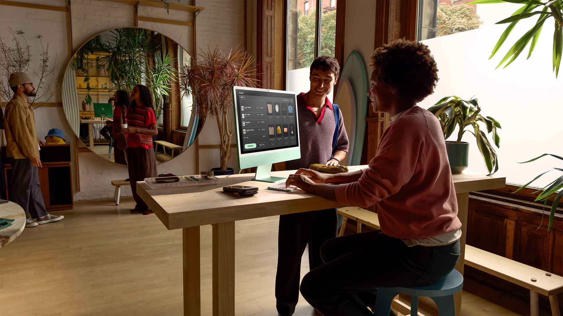 Two people in an office working on an Apple iMac M4