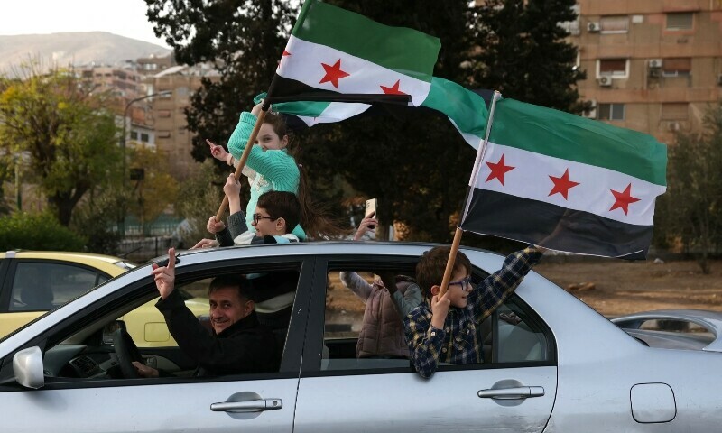 People celebrate with the Syrian opposition flag, in Damascus, on Dec 10, 2024.  — AFP