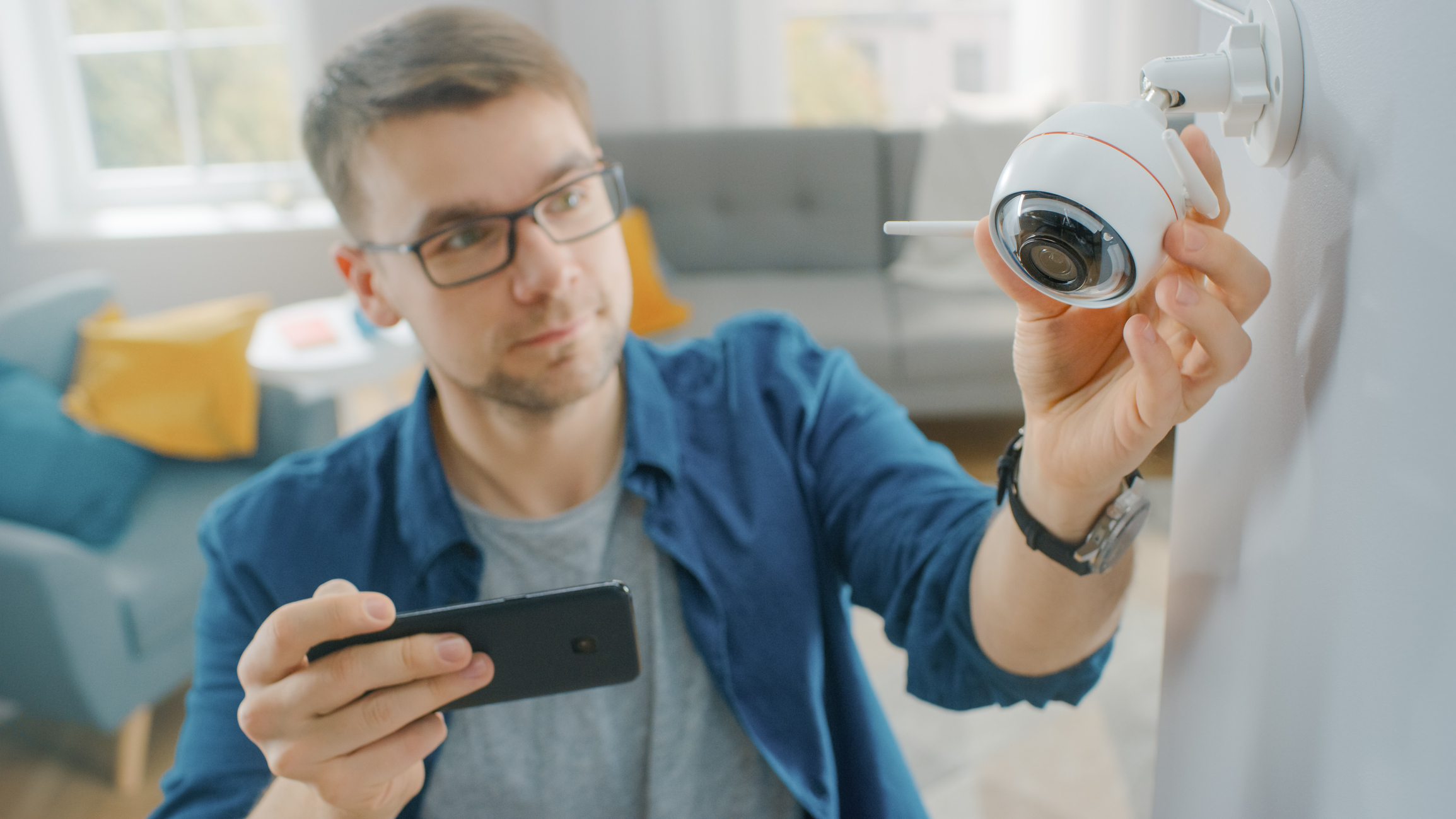 Man setting up home security camera with smartphone