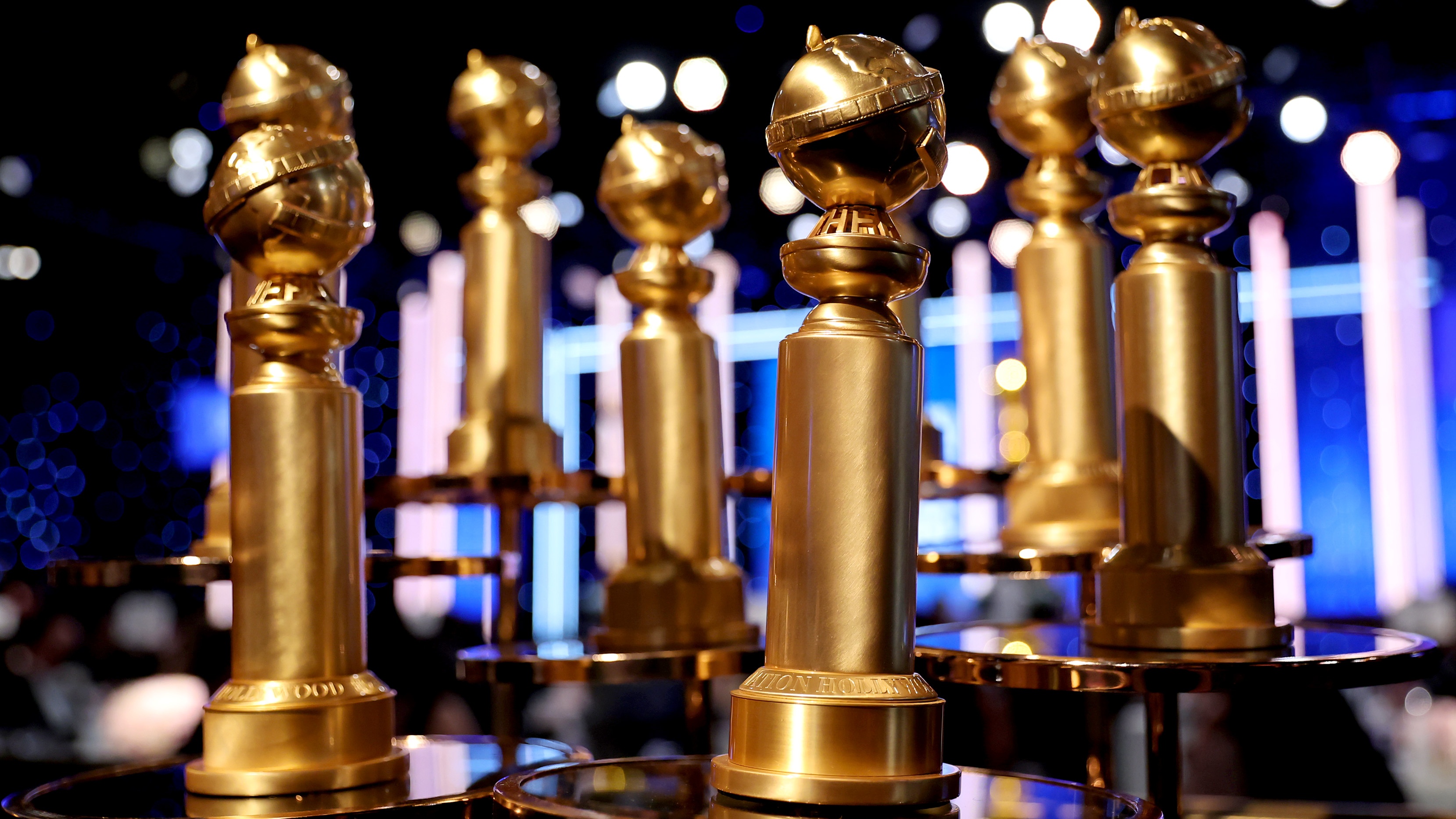 A collection of Golden Globes trophies displayed on a table in front of a stage