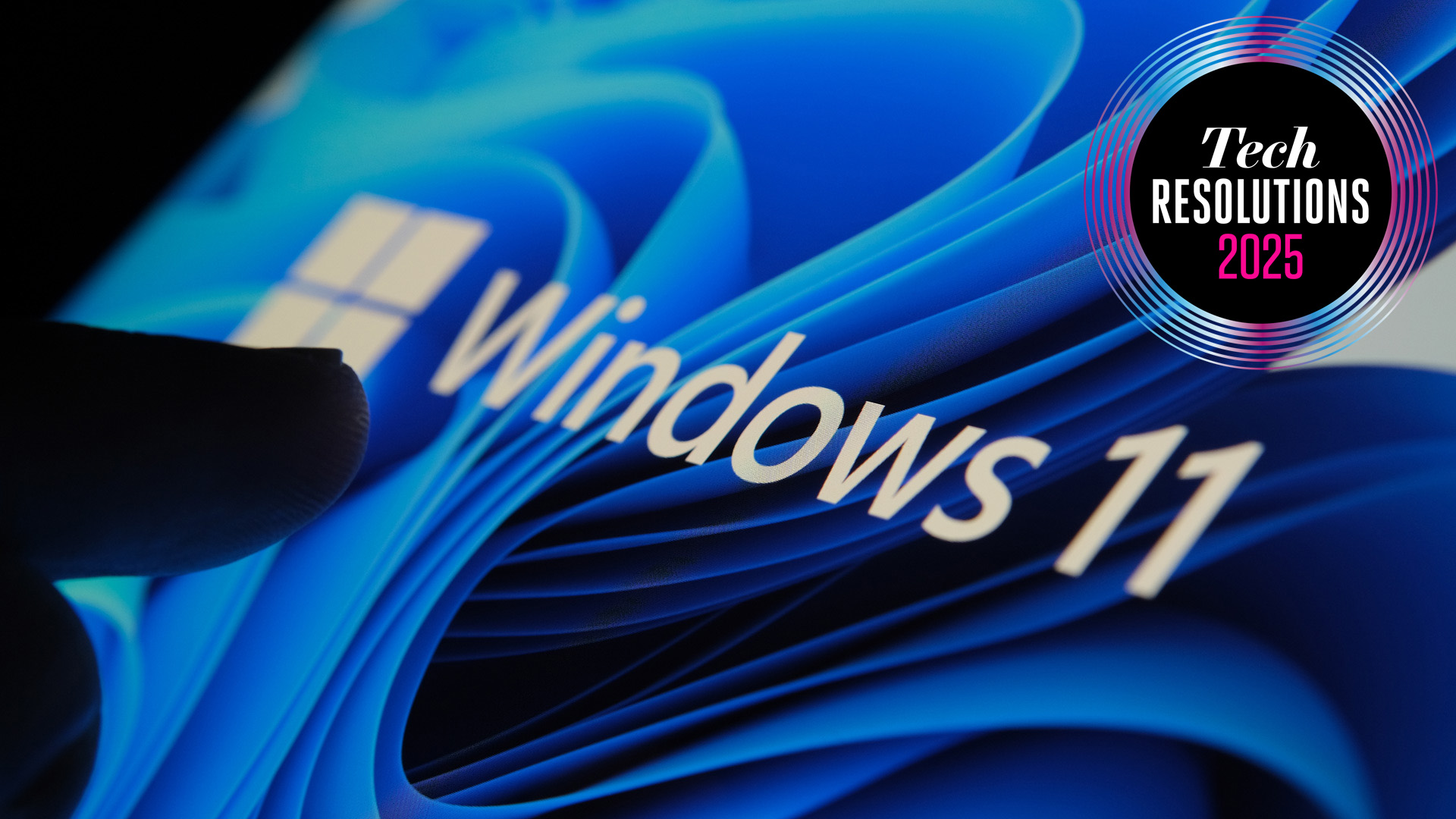 A finger touching a screen showing the Windows 11 logo