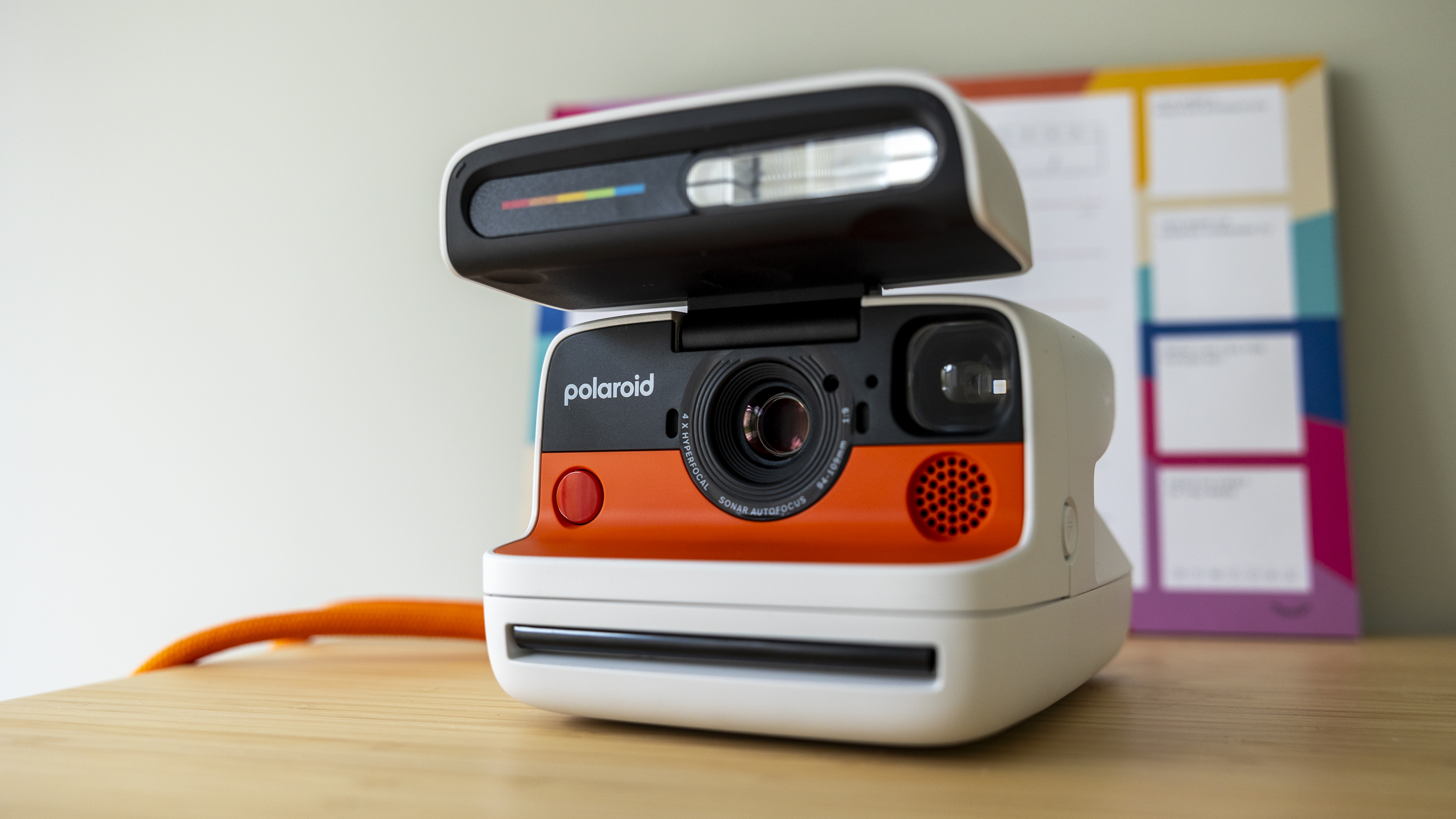 A white Polaroid Flip camera sits on a wooden desk