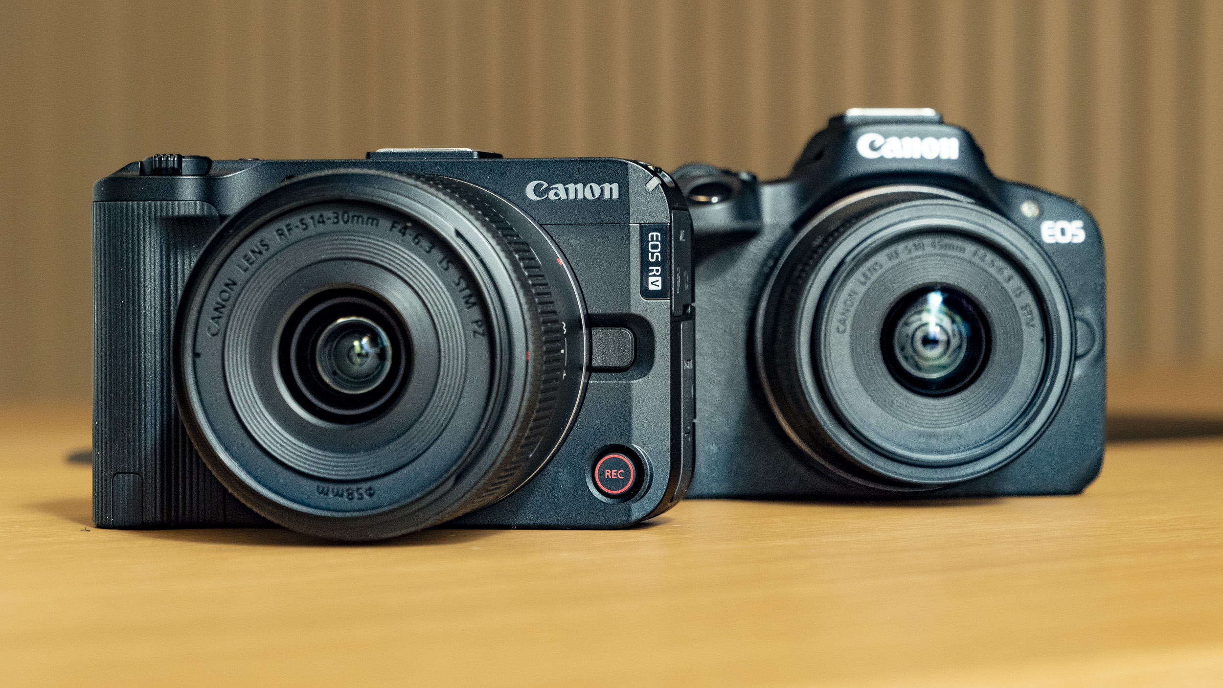 Canon EOS R50 V on a wooden table, alongside the EOS R50