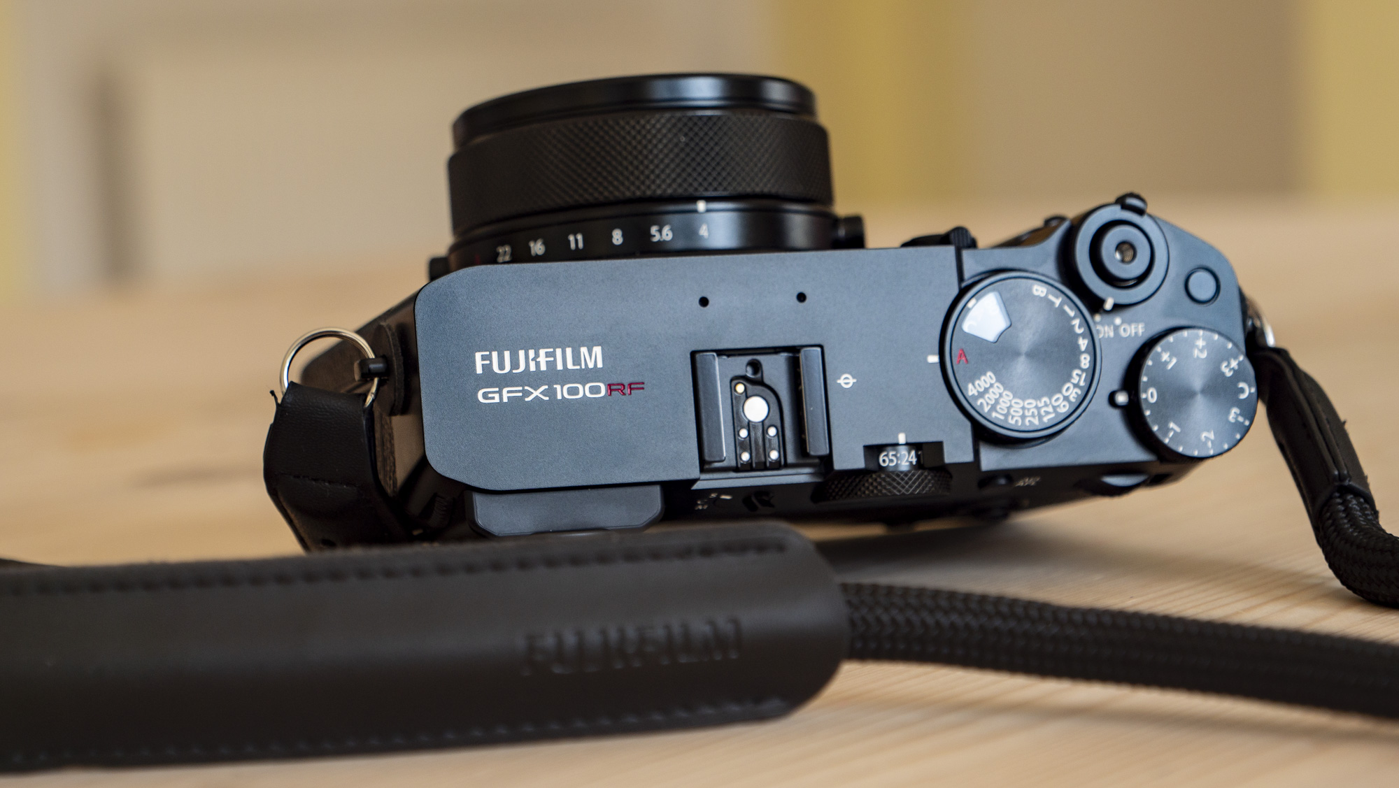 All-black Fujifilm GFX100RF rangefinder-style camera on a wooden table