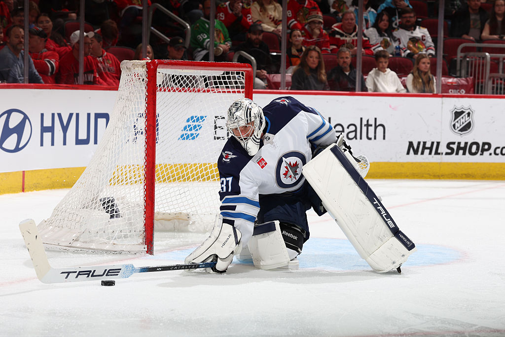 Goalie Connor Hellebuyck #37 of the Winnipeg Jets reaches for the puck in a game in April 2025
